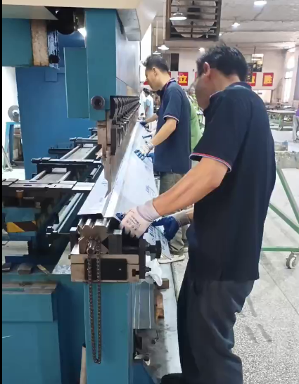 Long sheet metal bending in progress: workers position a 6-meter architectural panel on a 130T CNC press brake